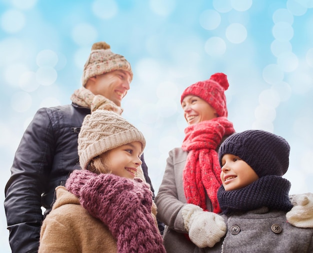 concepto de familia, infancia, temporada y personas - familia feliz con ropa de invierno sobre fondo de luces azules