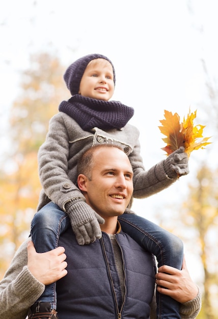 concepto de familia, infancia, temporada y personas - feliz padre e hijo divirtiéndose en el parque de otoño