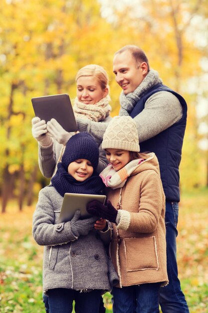 concepto de familia, infancia, temporada, tecnología y personas - familia feliz con computadoras tablet pc en el parque de otoño