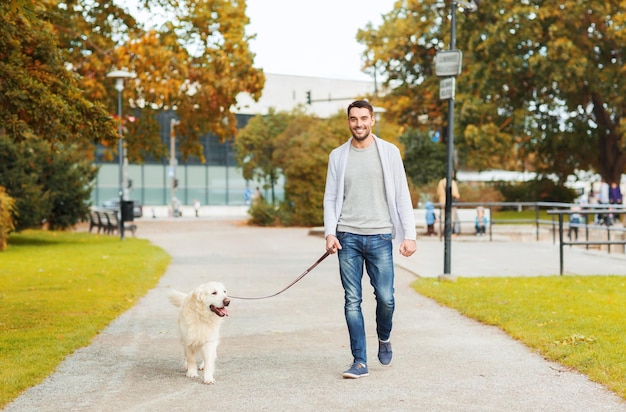 concepto de familia, mascota, animal doméstico, temporada y personas - hombre feliz con perro labrador retriever caminando en el parque de la ciudad de otoño