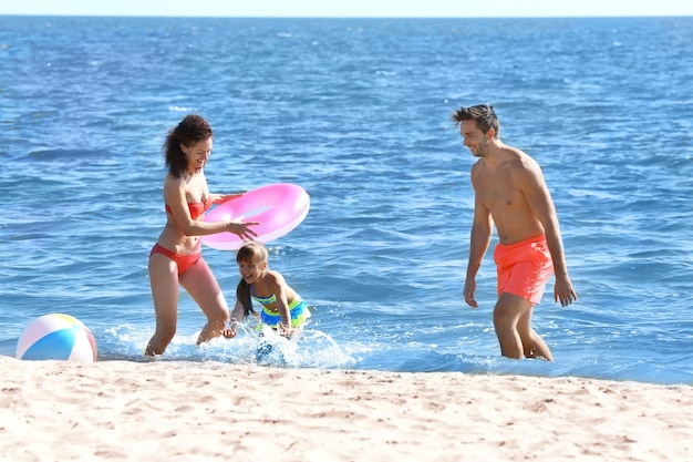 Concepto de familia Mujer joven hombre y niña jugando en la orilla del mar