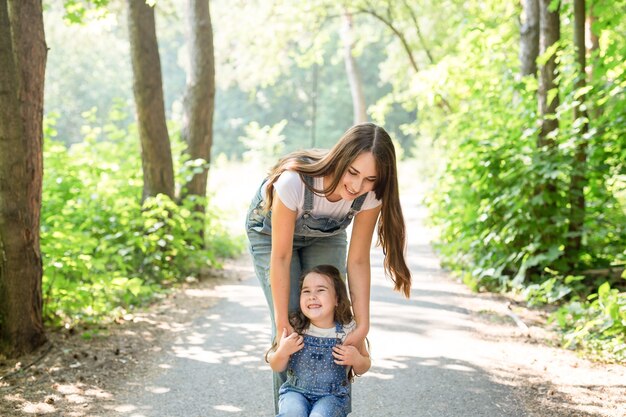 Concepto de familia y naturaleza - Madre con hija se divierten en el parque verde