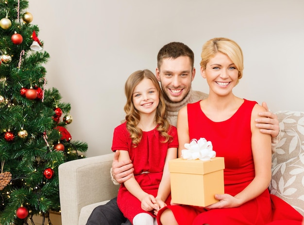 concepto de familia, navidad, felicidad y personas - familia sonriente en casa con caja de regalo