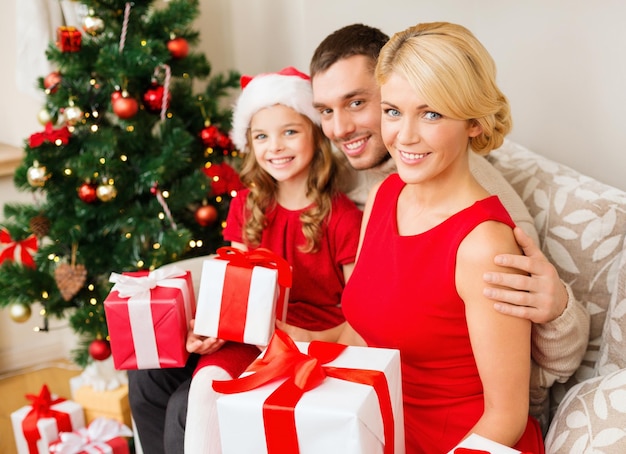 concepto de familia, navidad, navidad, felicidad y personas - familia sonriente con sombreros de ayudante de santa con muchas cajas de regalo