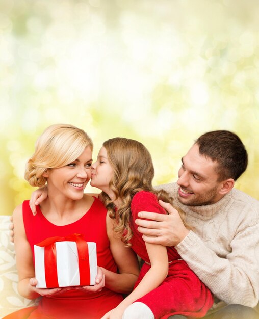 concepto de familia, navidad, navidad, invierno, felicidad y personas: una niña adorable besa a su madre y le da un regalo