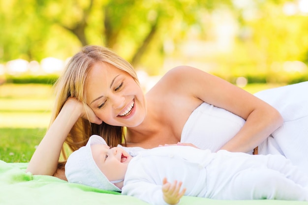 concepto de familia, niño y paternidad - madre feliz acostada con un bebé en una manta en el parque