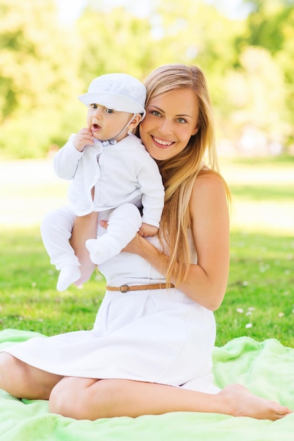 concepto de familia, niño y paternidad - madre feliz con un bebé sentado en una manta en el parque