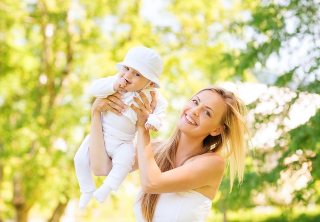 concepto de familia, niño y paternidad - madre feliz sosteniendo y criando a un bebé en el parque