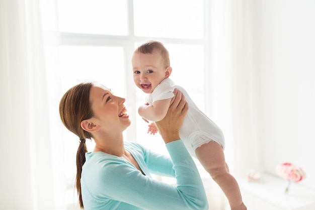 concepto de familia, niño y paternidad - madre joven feliz y sonriente con un bebé pequeño en casa