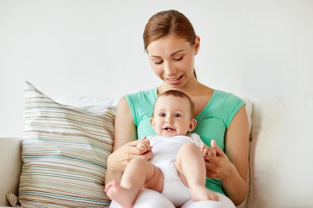 concepto de familia, niño y paternidad - madre joven feliz y sonriente con un bebé pequeño en casa