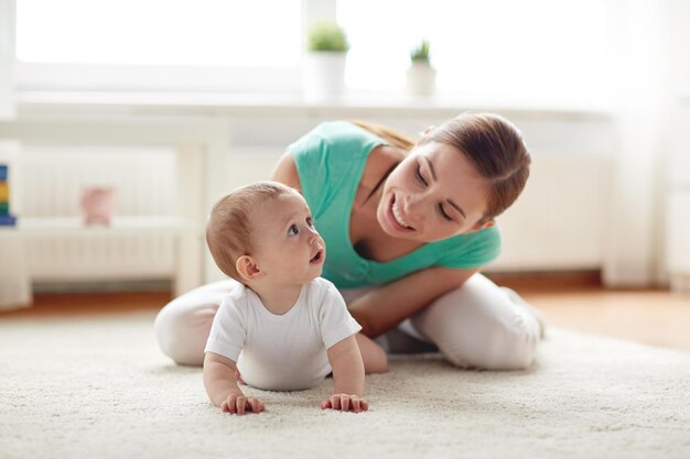 concepto de familia, niño y paternidad - madre joven sonriente feliz jugando con el bebé en casa