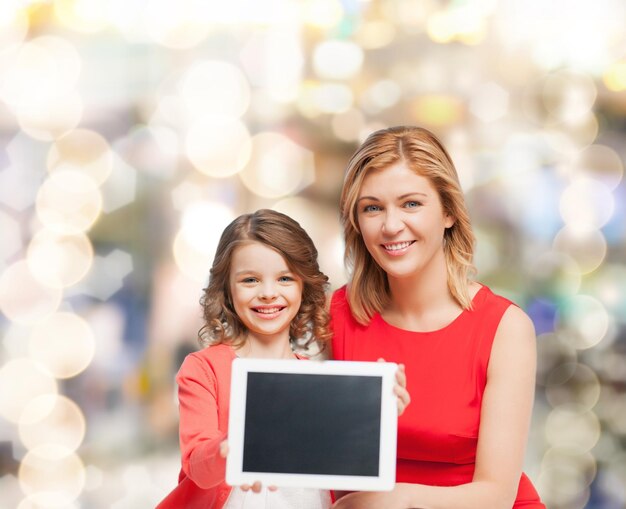 concepto de familia, niño y tecnología - madre e hija sonrientes con computadoras tablet pc pantalla negra en blanco