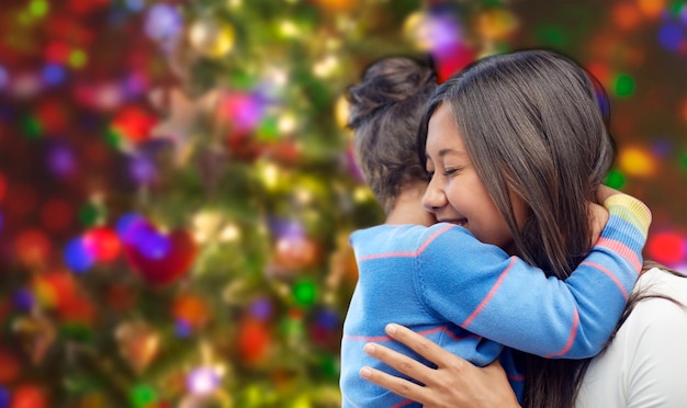 Foto concepto de familia, niños, amor y gente feliz - feliz madre e hija abrazándose sobre el fondo de las luces