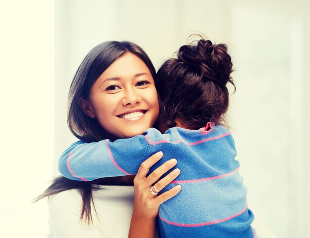 concepto de familia, niños y gente feliz - abrazando a madre e hija