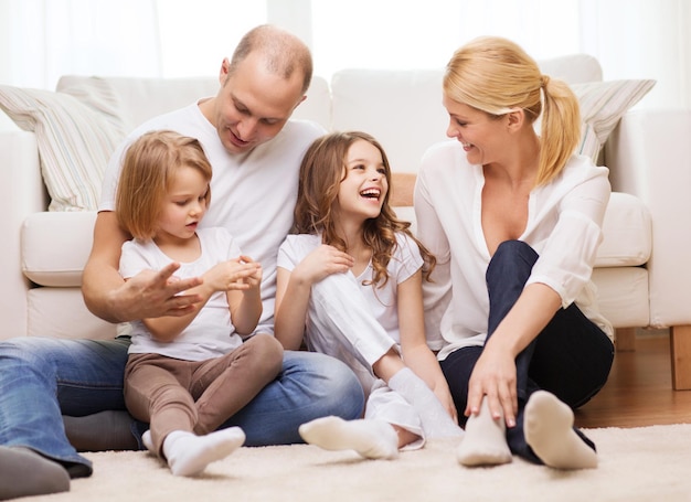 concepto de familia, niños y hogar - familia sonriente con dos niñas pequeñas sentadas en el suelo en casa