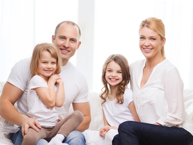 concepto de familia, niños y hogar - padres sonrientes y dos niñas en casa