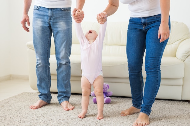 Concepto de familia, niños y paternidad: padres que enseñan a caminar a la niña.