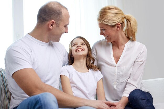 concepto de familia, niños y personas - padres felices con una hija pequeña en casa