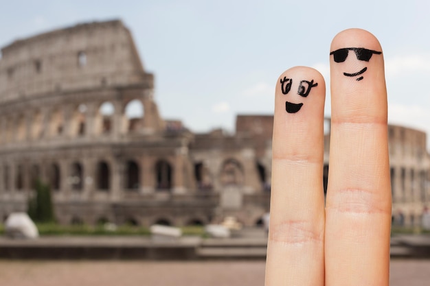 concepto de familia, pareja, viajes, turismo y partes del cuerpo - cierre de dos dedos con caras sonrientes sobre el coliseo en el fondo de roma