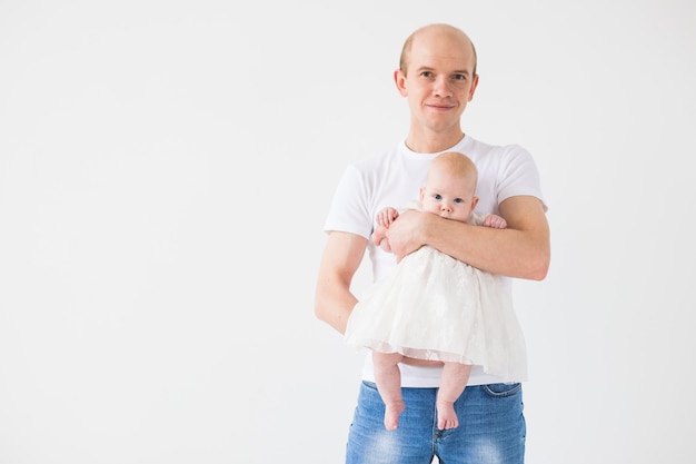 concepto de familia, paternidad e hijos - padre calvo sosteniendo lindo recién nacido en superficie blanca con