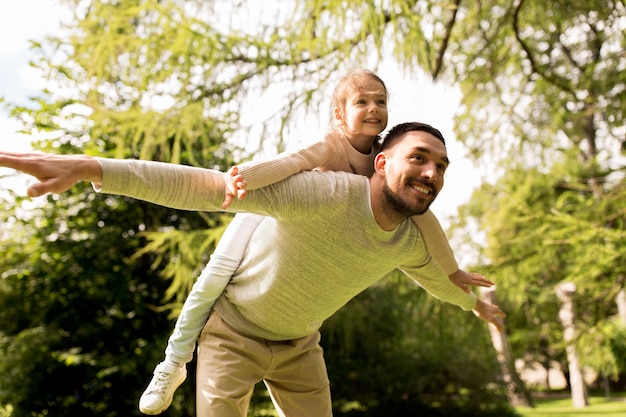 concepto de familia, paternidad, patria y gente - hombre feliz y niña pequeña divirtiéndose en el parque de verano