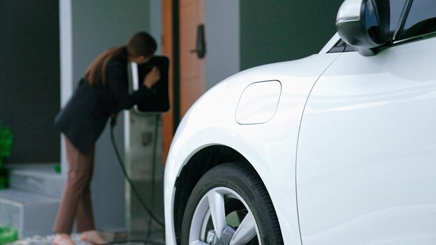 Concepto de una familia progresista con una estación de carga doméstica para un vehículo eléctrico que fomenta un medio ambiente saludable y limpio El vehículo eléctrico impulsado por tecnología de energía limpia sostenible