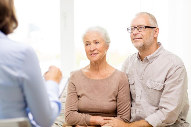 concepto de familia, relaciones, edad y personas - feliz pareja mayor y psicólogo o trabajador social en casa