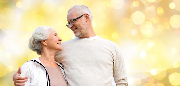 concepto de familia, relaciones, edad y personas - feliz pareja mayor sobre fondo de luces navideñas