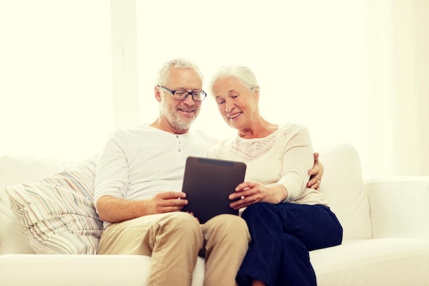 concepto de familia, tecnología, edad y personas - feliz pareja de ancianos con tablet pc en casa