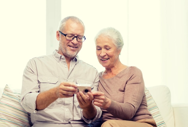 concepto de familia, tecnología, edad y personas - feliz pareja mayor con cámara en casa