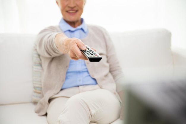 concepto de familia, tecnología, televisión, edad y personas - cerca de una anciana feliz viendo la televisión en casa