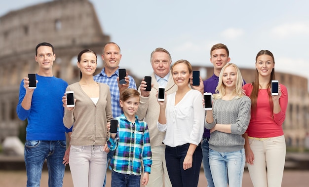 Foto concepto de familia, tecnología, viajes y turismo - grupo de personas sonrientes con smartphones sobre el fondo del coliseo