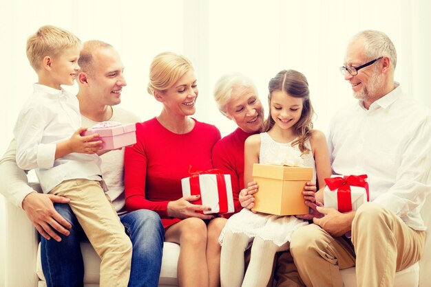 Foto concepto de familia, vacaciones, generación, navidad y personas - familia sonriente con cajas de regalo sentadas en el sofá en casa