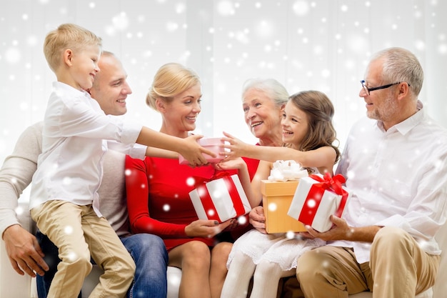 concepto de familia, vacaciones, generación, navidad y personas - familia sonriente con cajas de regalo sentadas en el sofá en casa