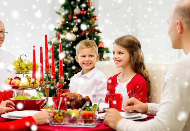 concepto de familia, vacaciones, generación, navidad y personas - familia sonriente cenando en casa