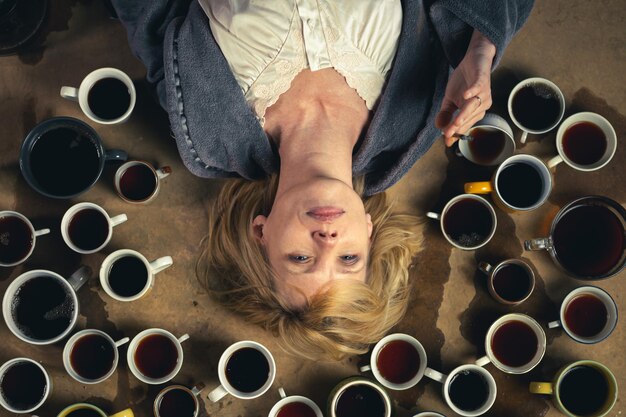 El concepto de una fecha límite, la necesidad de permanecer alegre Mujer rodeada de muchas tazas de café