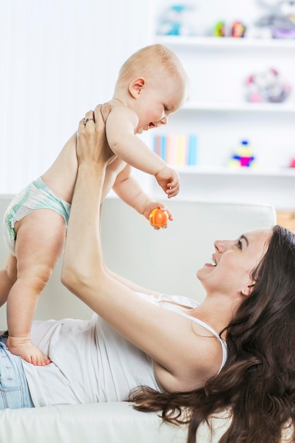 Concepto de felicidad: madre feliz jugando con un bebé de un año en la habitación para niños