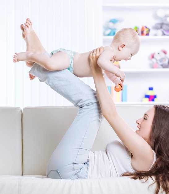 Concepto de felicidad madre feliz jugando con un bebé de un año en la habitación para niños