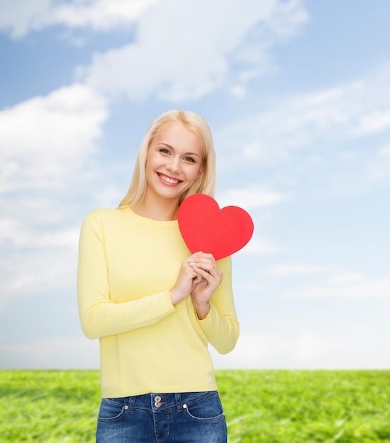 concepto de felicidad, salud y amor - mujer sonriente con corazón rojo