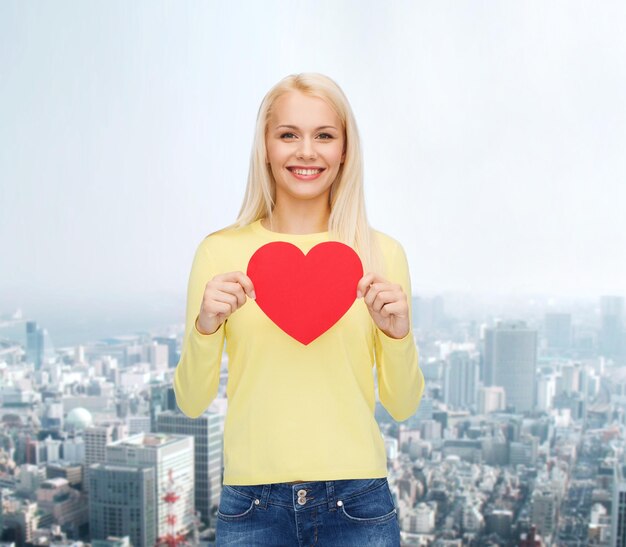 concepto de felicidad, salud y amor - mujer sonriente con corazón rojo