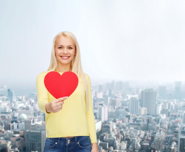 concepto de felicidad, salud y amor - mujer sonriente con corazón rojo