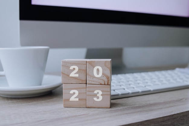 Concepto de feliz año nuevo. Cubo de madera con el número 2023 con café en el escritorio de la oficina.