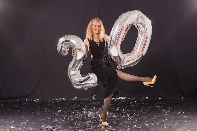 Concepto de feliz cumpleaños - hermosa mujer joven con 20 globos en forma de número.