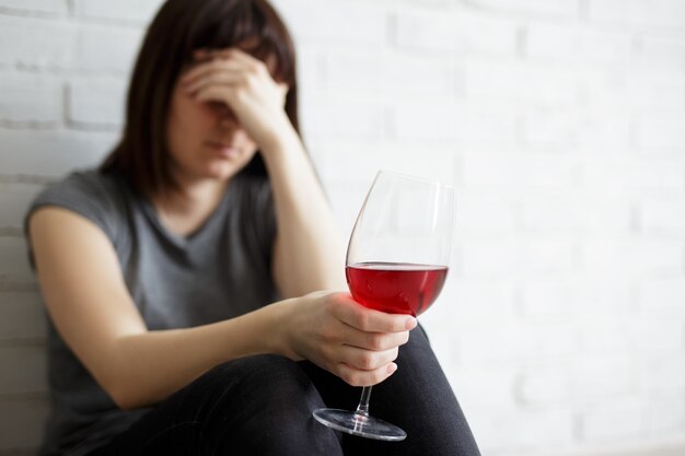 Concepto femenino de alcoholismo, relación, divorcio y depresión - mujer estresada llorando y bebiendo vino en casa