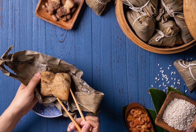 Concepto del Festival del Bote del Dragón Zongzi Bola de masa hervida de arroz comida tradicional china sobre fondo de madera azul para el concepto de diseño plano de la vista superior del Festival Duanwu