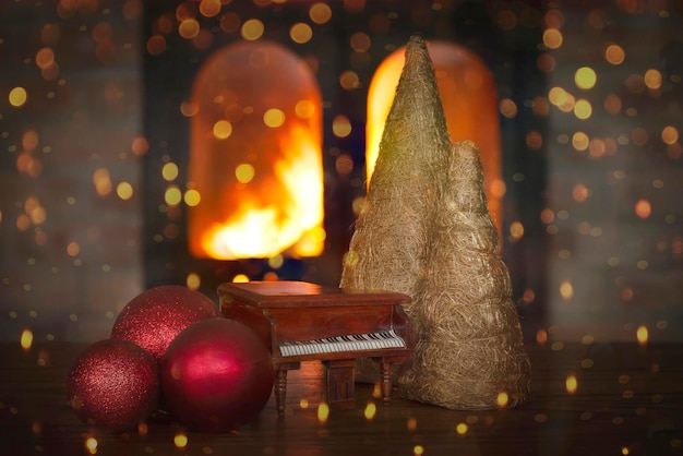 Concepto festivo de Navidad con figuras orgánicas de piano de cola en miniatura de árboles de Navidad y decoraciones en el fondo borroso de la chimenea ardiente con bokeh