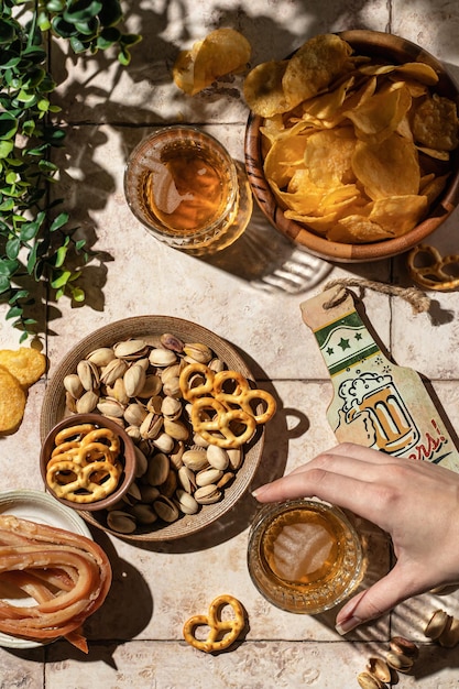 Concepto de fiesta al aire libre de cerveza La mano de la mujer toma un vaso de cerveza de la mesa con diferentes bocadillos