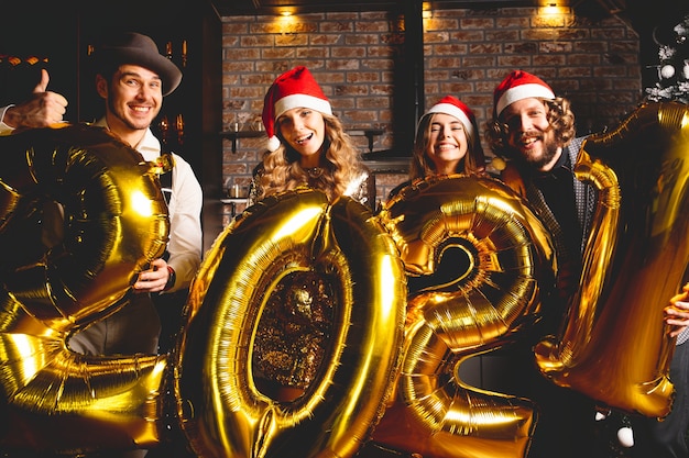 Concepto de fiesta, gente y vacaciones de año nuevo: mujeres y hombres celebrando la víspera de año nuevo 2021.