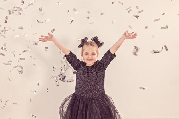 Concepto de fiesta, vacaciones, año nuevo y celebración - Niña lanzando confeti.