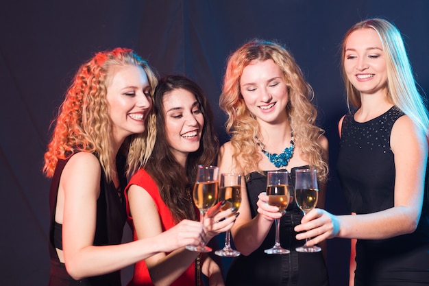 Concepto de fiesta, vacaciones, celebración y fin de año - alegre joven tintineo de copas de champán en la fiesta.